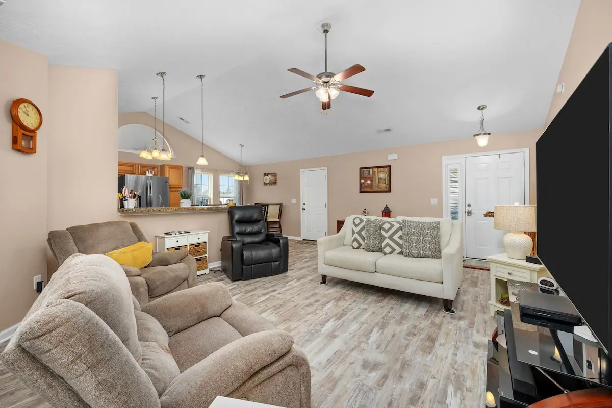 Living room with gray seating, white sofa, and ceiling fan