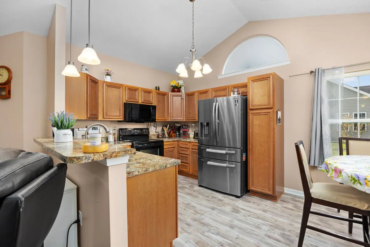 Wood-cabinet kitchen with stone-look counters and nearby dining table