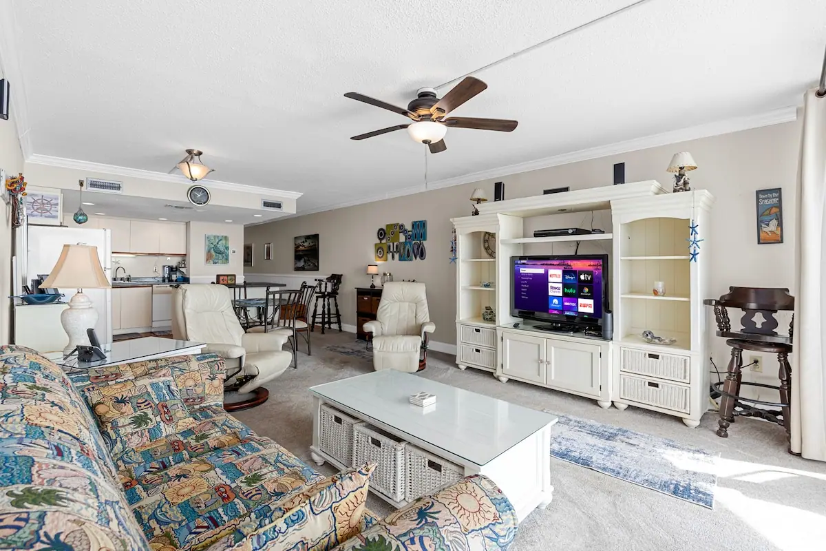 Living room with patterned sofa, white television cabinet, and armchairs