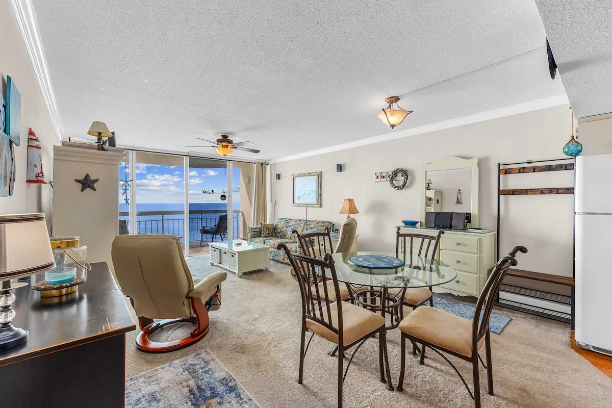 Round glass dining table in a living room with ocean balcony doors