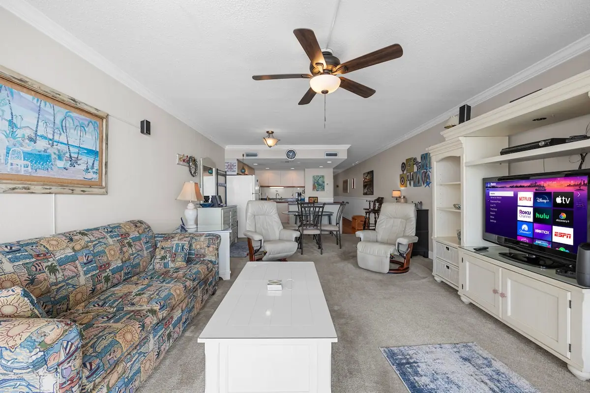 Patterned sofa, white coffee table, and television in a long living room