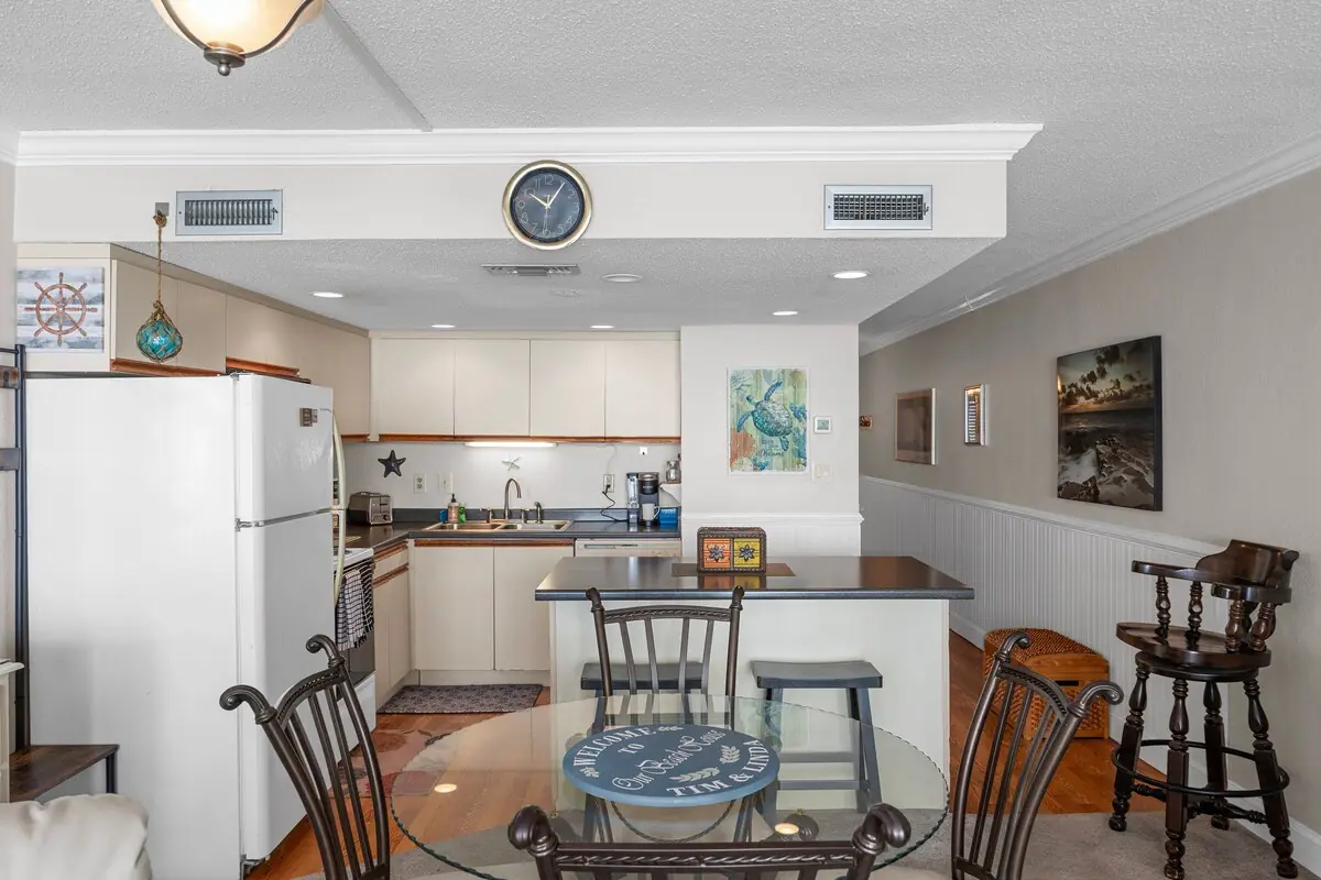 Round glass dining table beside a white kitchen and breakfast bar