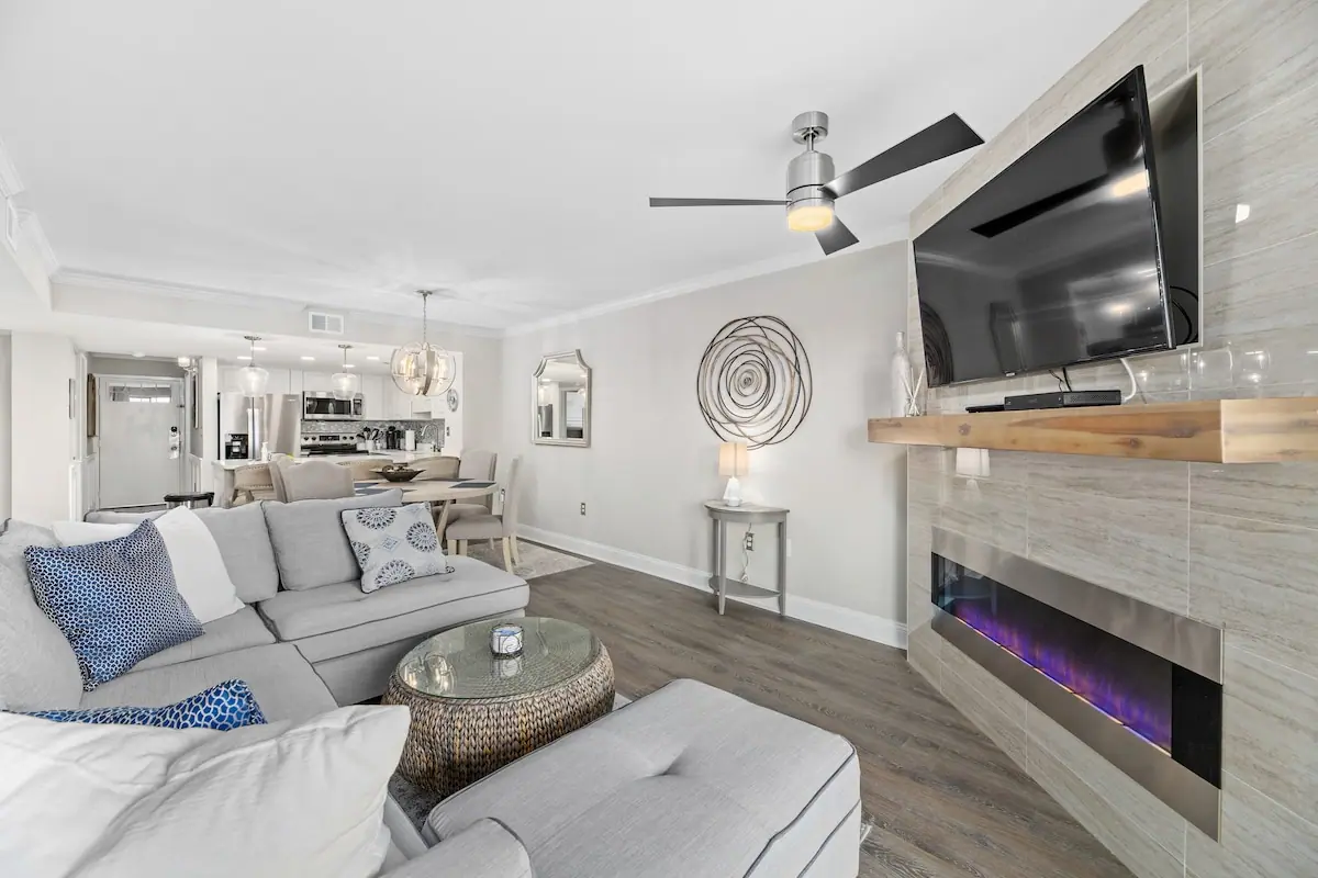 Living room with a pale sofa, television, and electric fireplace