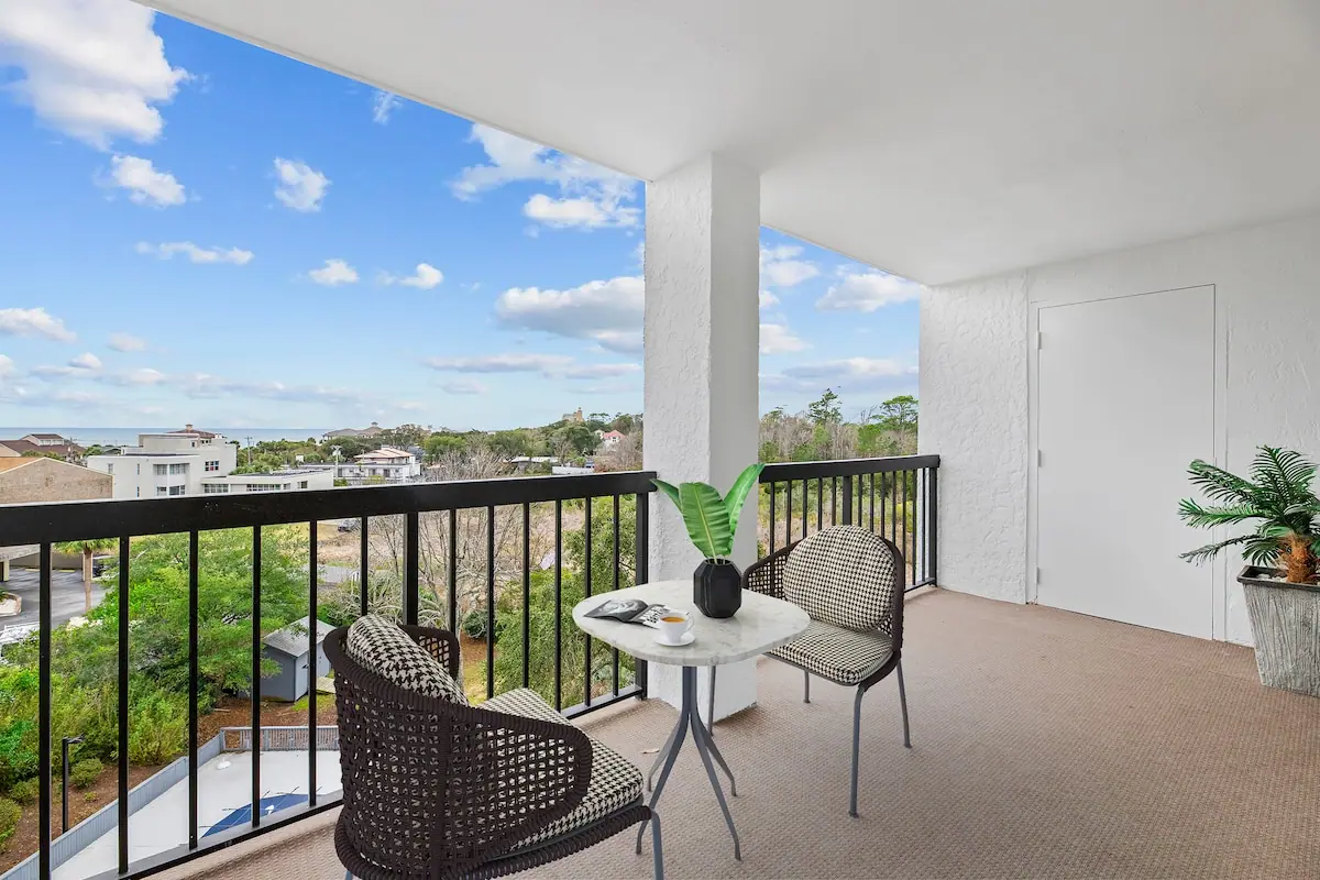 Wide balcony with wicker chairs and rooftops beyond the railing