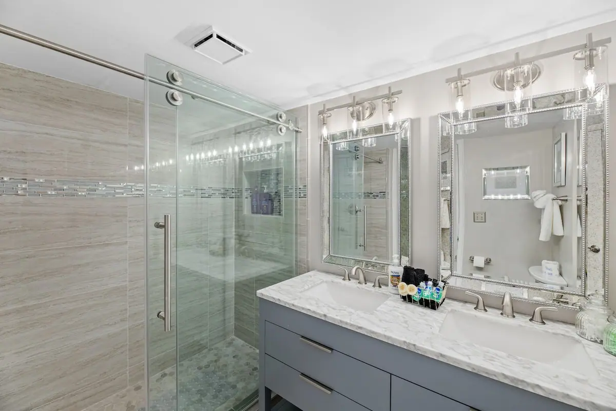 Bathroom with glass shower, double sink vanity, and large mirror