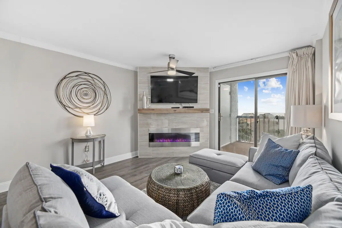 Gray sectional seating around woven coffee table beside the fireplace