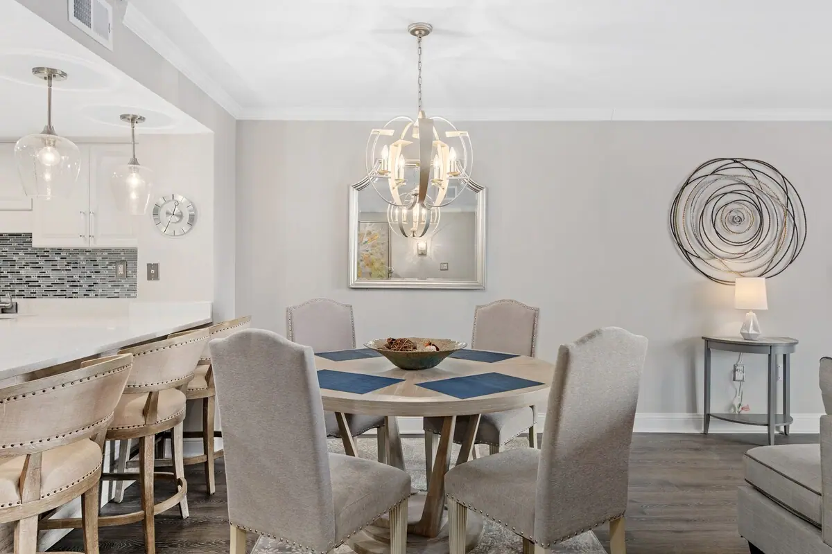 White dining chairs around a round table beside the breakfast bar