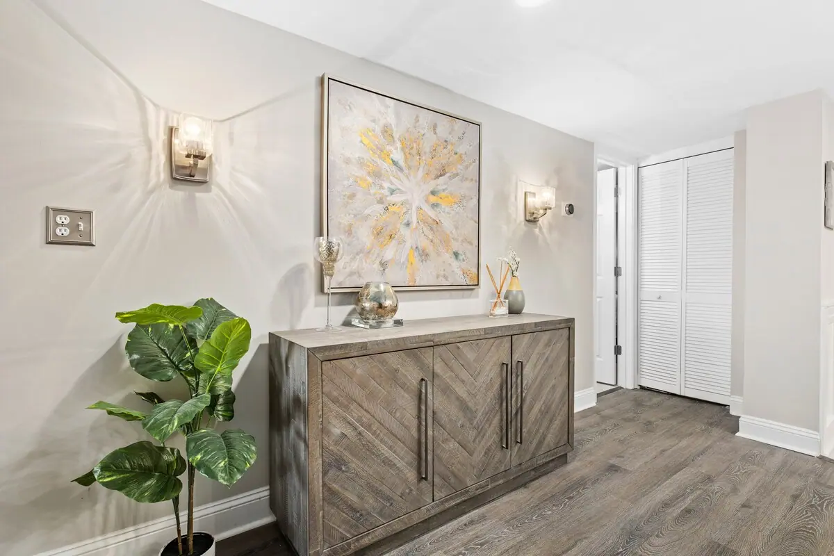 Entry hall with wood credenza, floral arrangement, and wall artwork