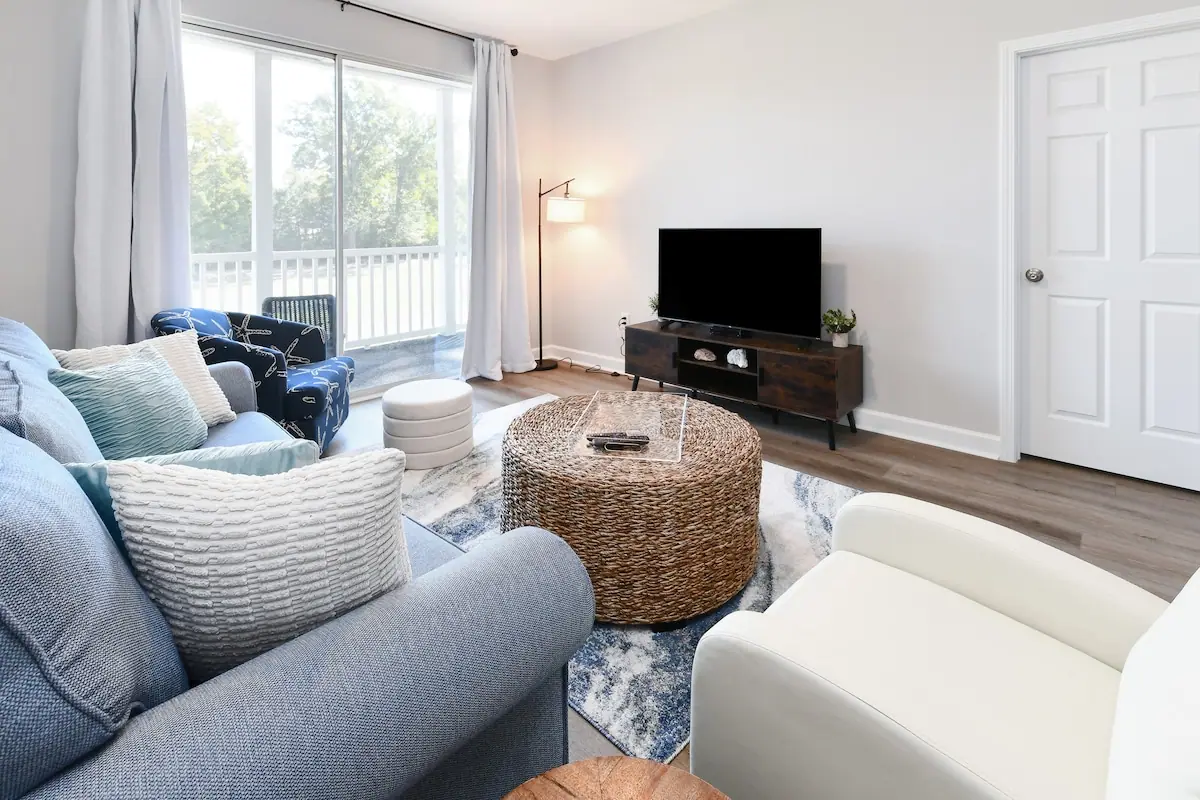 Living room with blue seating, a wicker coffee table, and a television