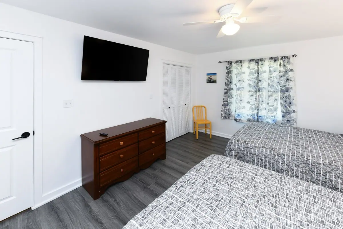 Bedroom with patterned beds, a dresser, and wall-mounted television
