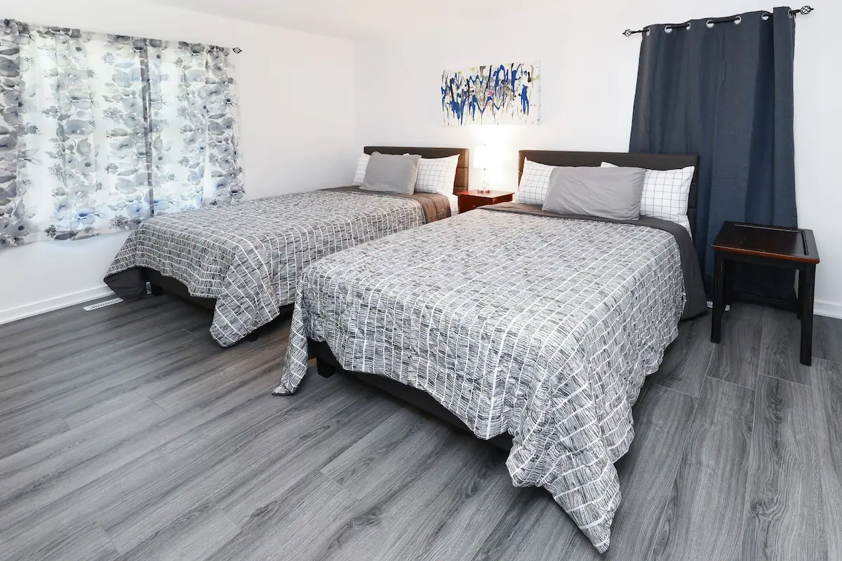 Bedroom with two beds, patterned gray spreads, and blue artwork
