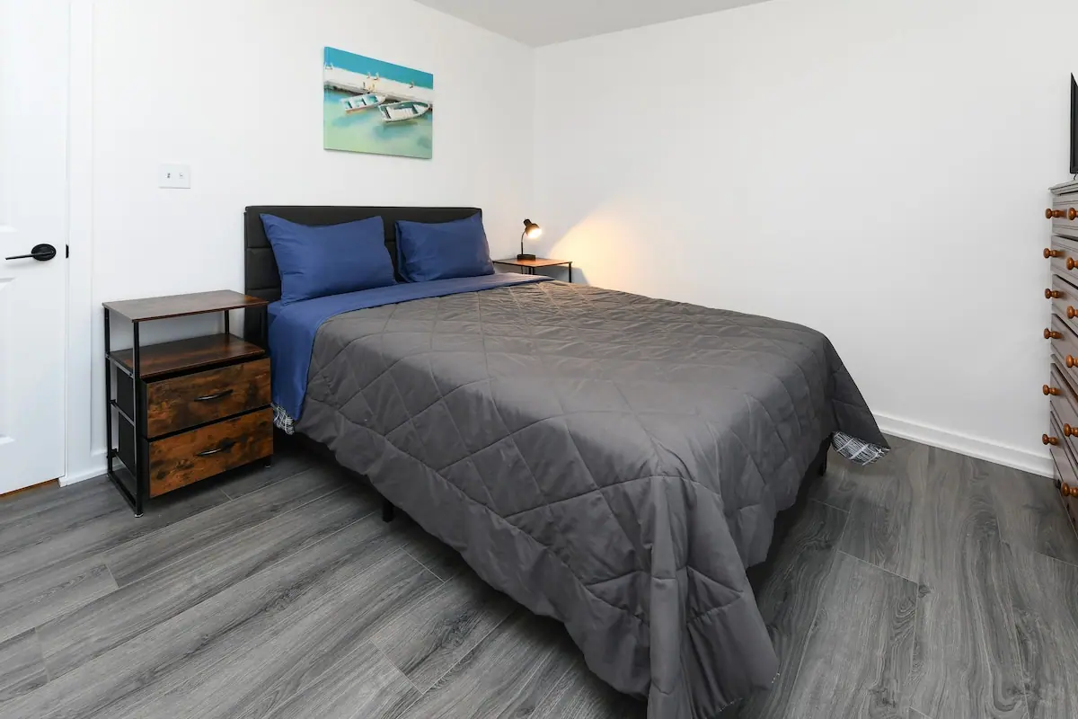 Bedroom with gray bedspread, blue pillows, and bedside tables