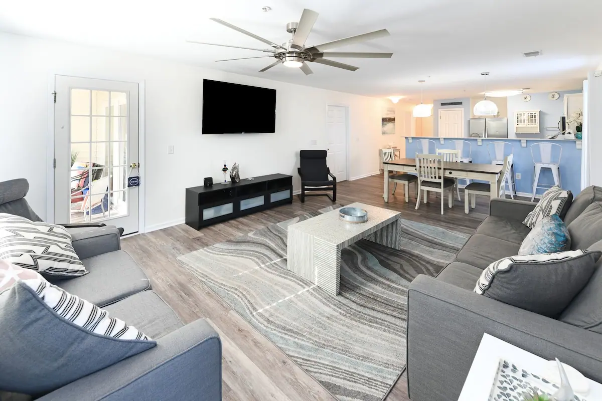 Open-plan living room with gray sofas and a blue kitchen