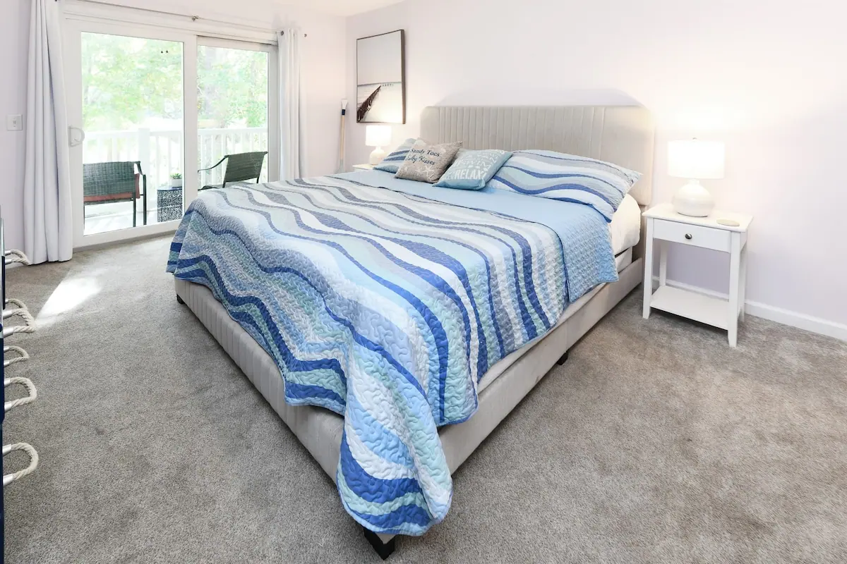 Bedroom with blue striped bedcover and sliding patio door