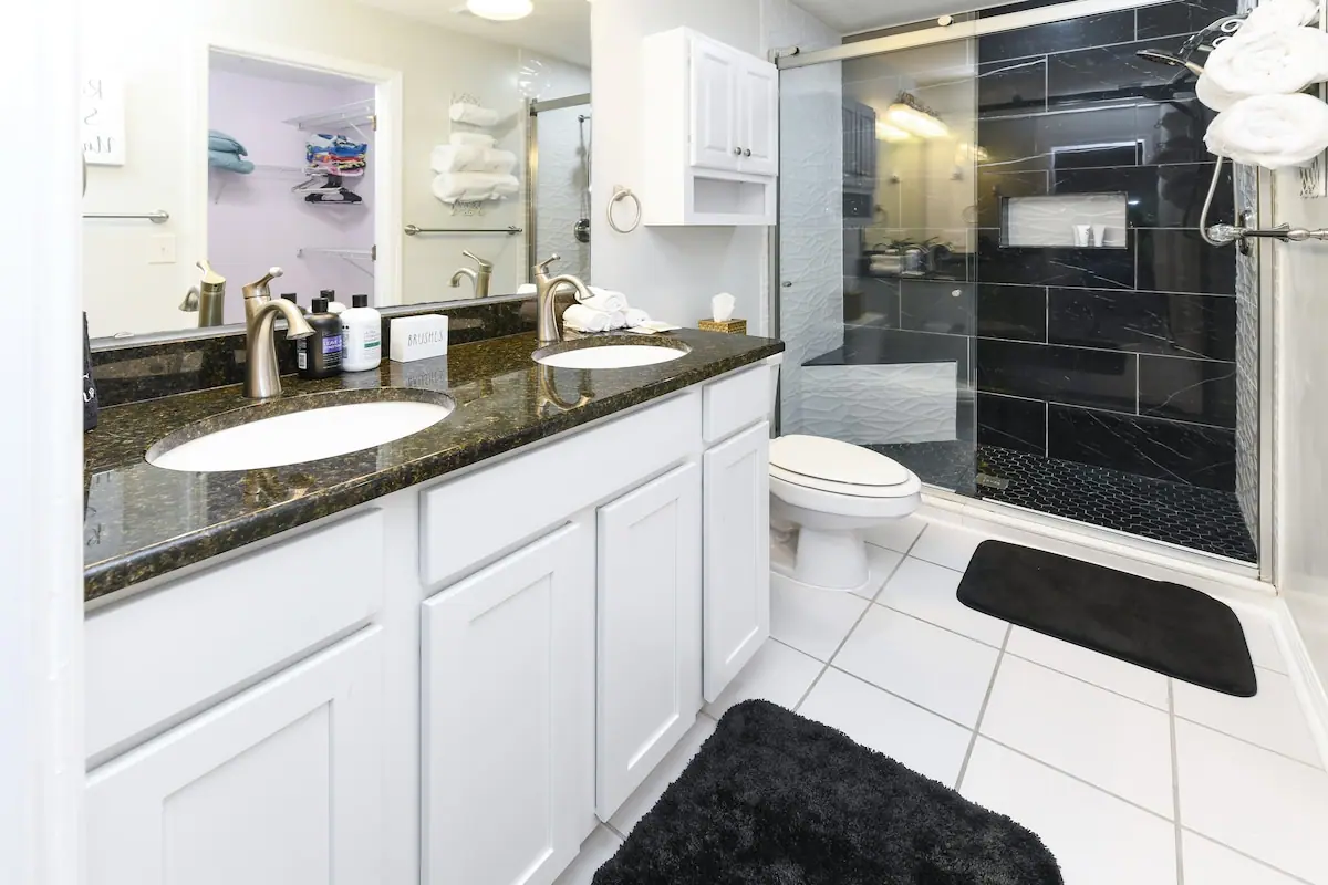 Bathroom with two sinks and a dark-tiled walk-in shower