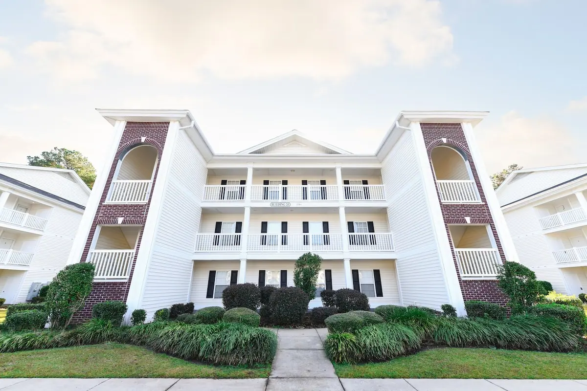 Exterior of a three-story white condo building with landscaped entry