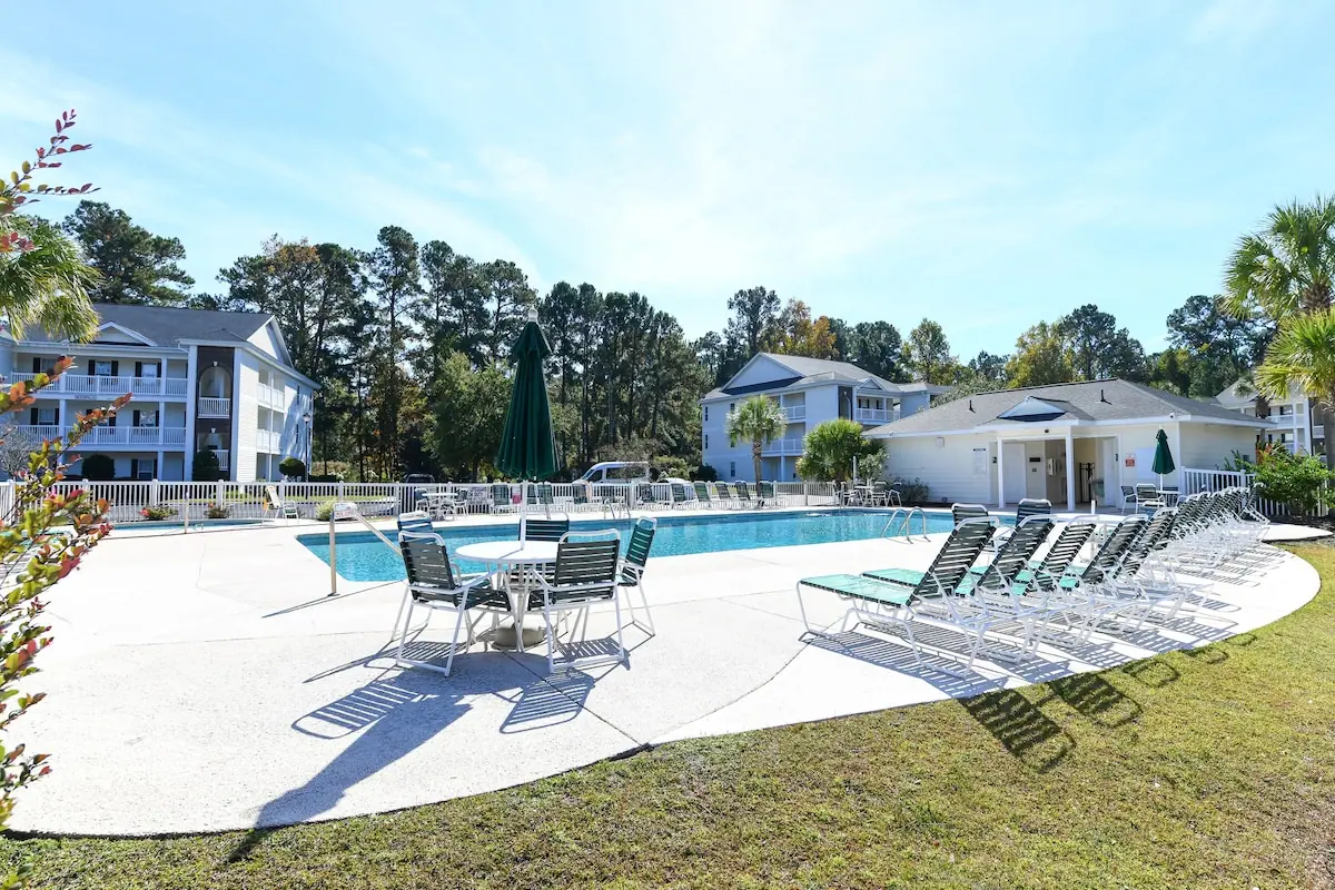 Outdoor pool and patio with lounge chairs and umbrella tables