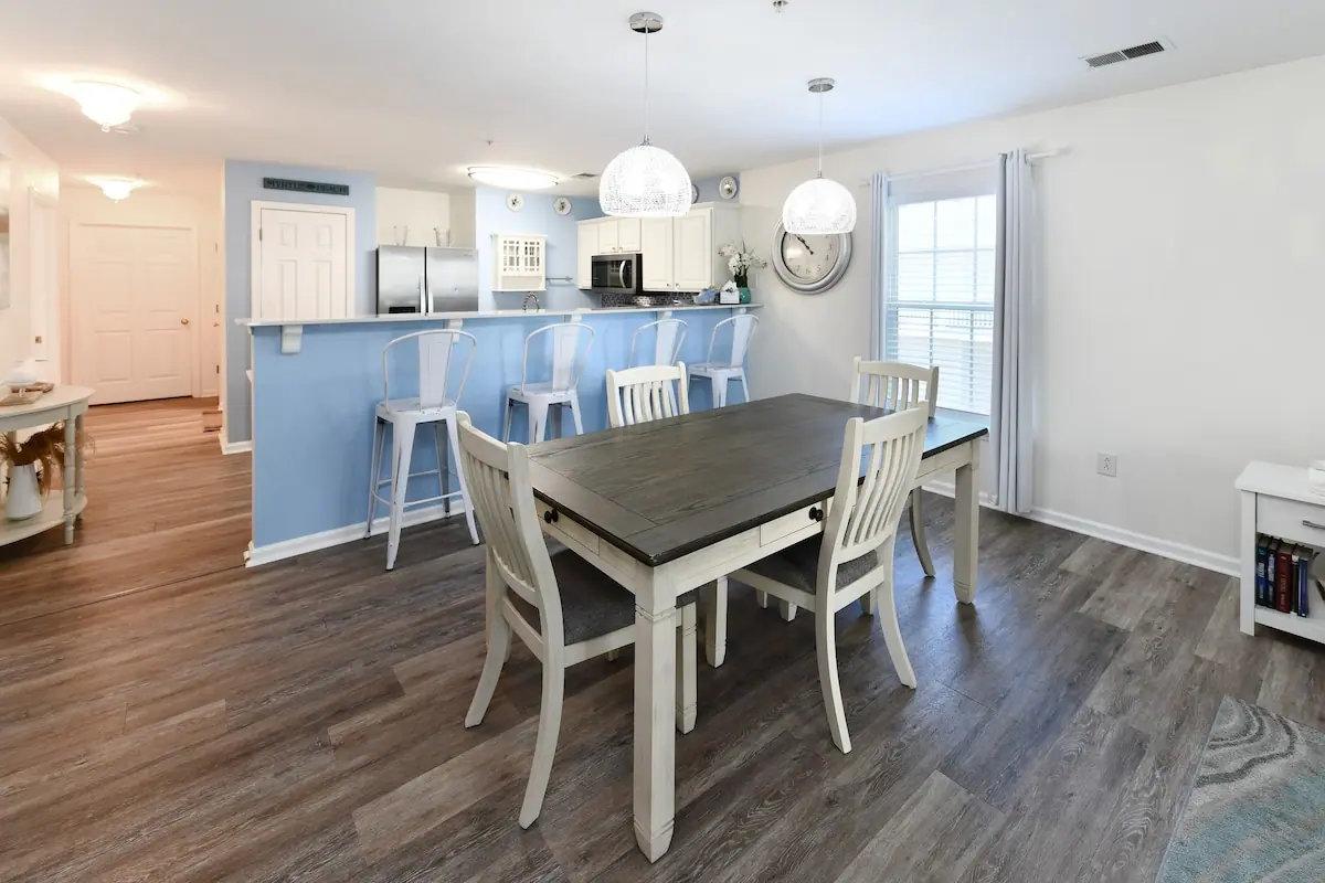 Dining table with white chairs and blue breakfast bar behind