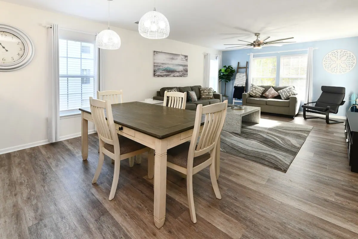 Open dining and living space with wood table, gray sofas, and windows