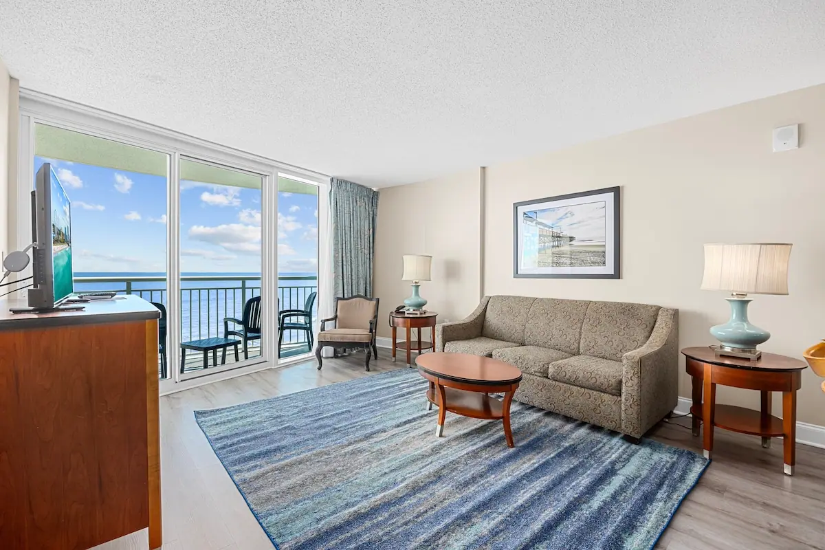 Living room with a patterned sofa and glass doors to an ocean-facing balcony