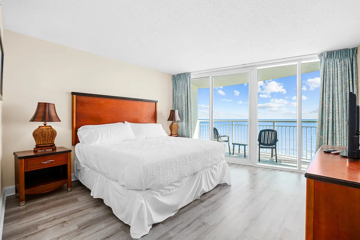 Bedroom with white bed and glass doors to an ocean-facing balcony