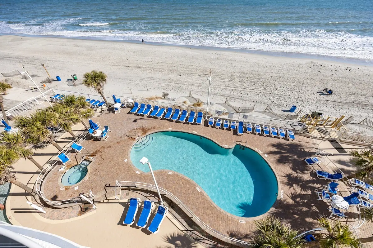 Pool deck with blue loungers overlooking the beach and ocean