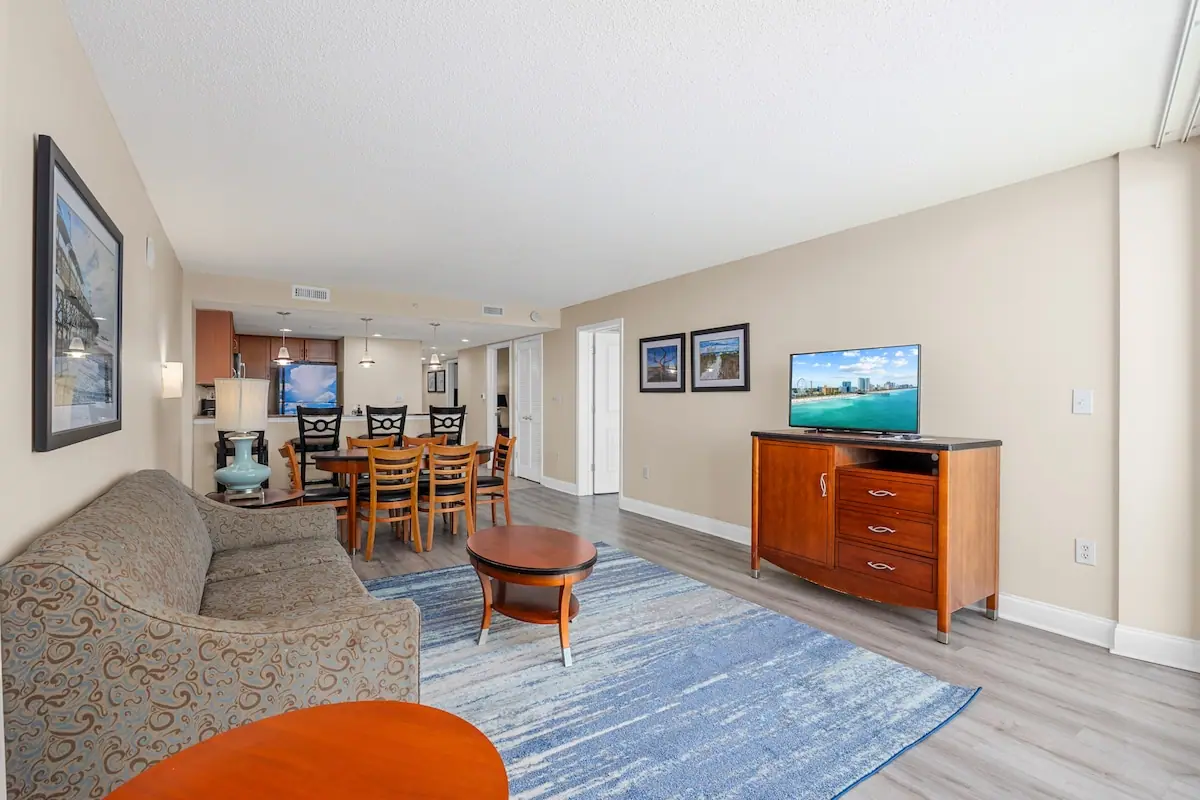 Living and dining room with kitchen and ocean-facing balcony beyond