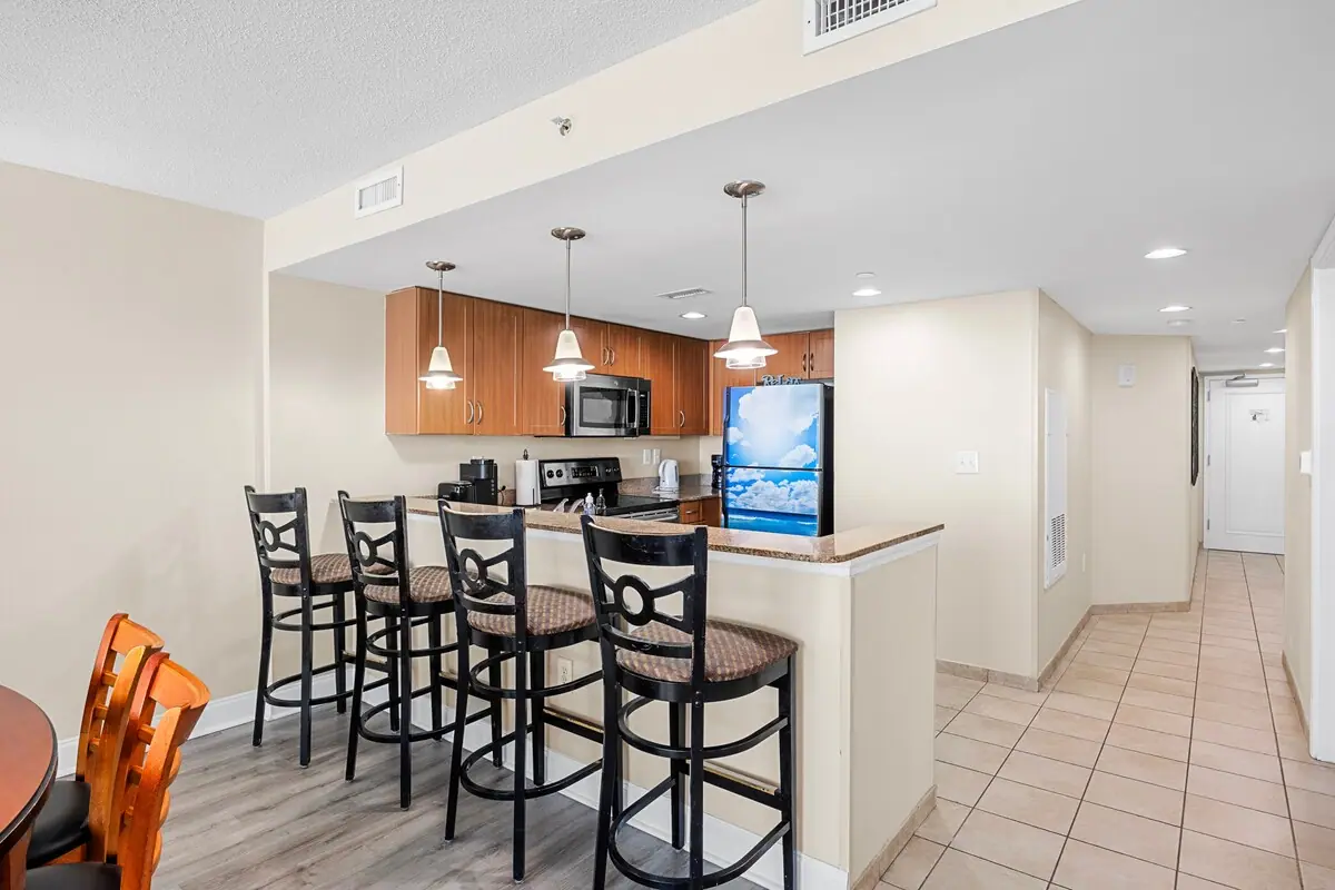 Breakfast bar with four chairs beside a wood-cabinet kitchen