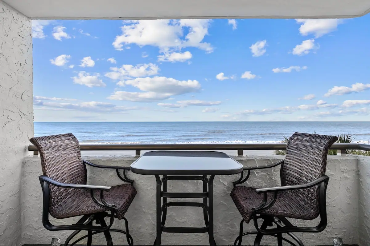 Balcony with two chairs and a table overlooking the ocean
