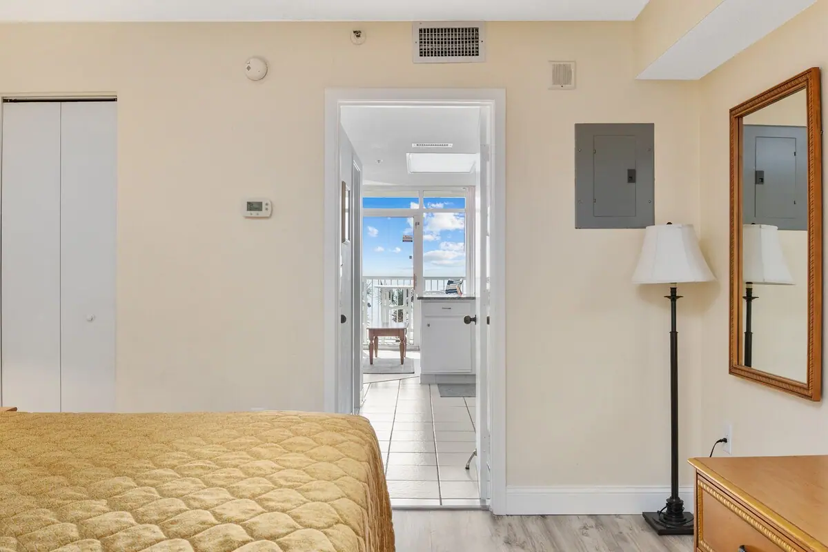 Yellow-covered bed with a doorway toward a bright room and balcony