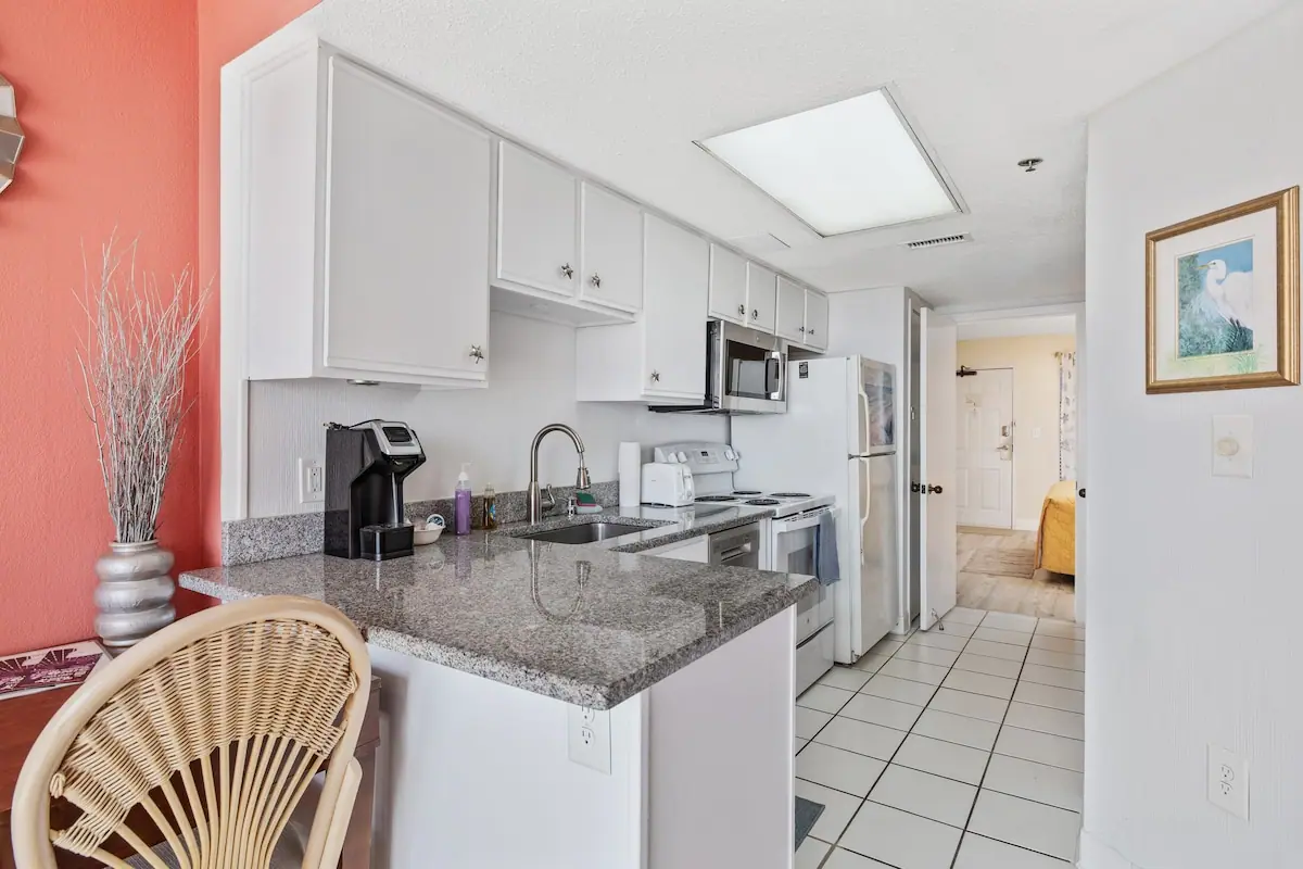 White galley kitchen with a breakfast bar, sink, stove, and refrigerator