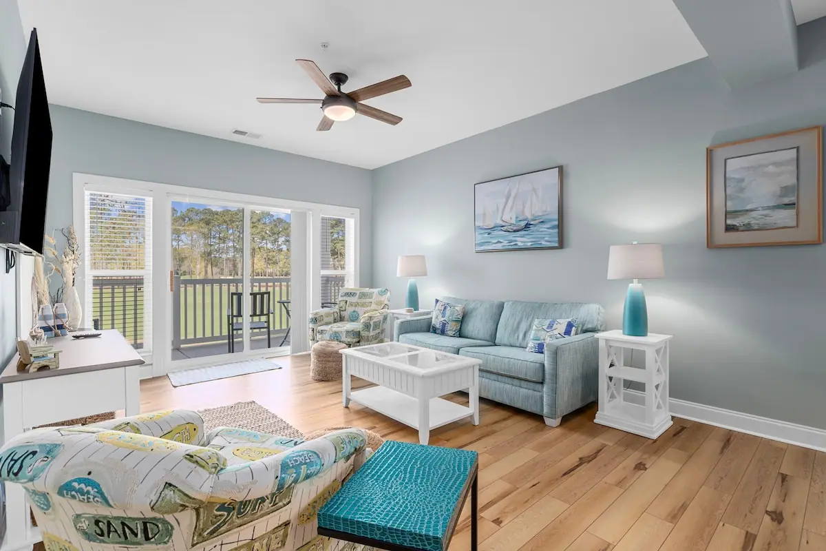 Living room with a pale blue sofa and glass doors to a balcony