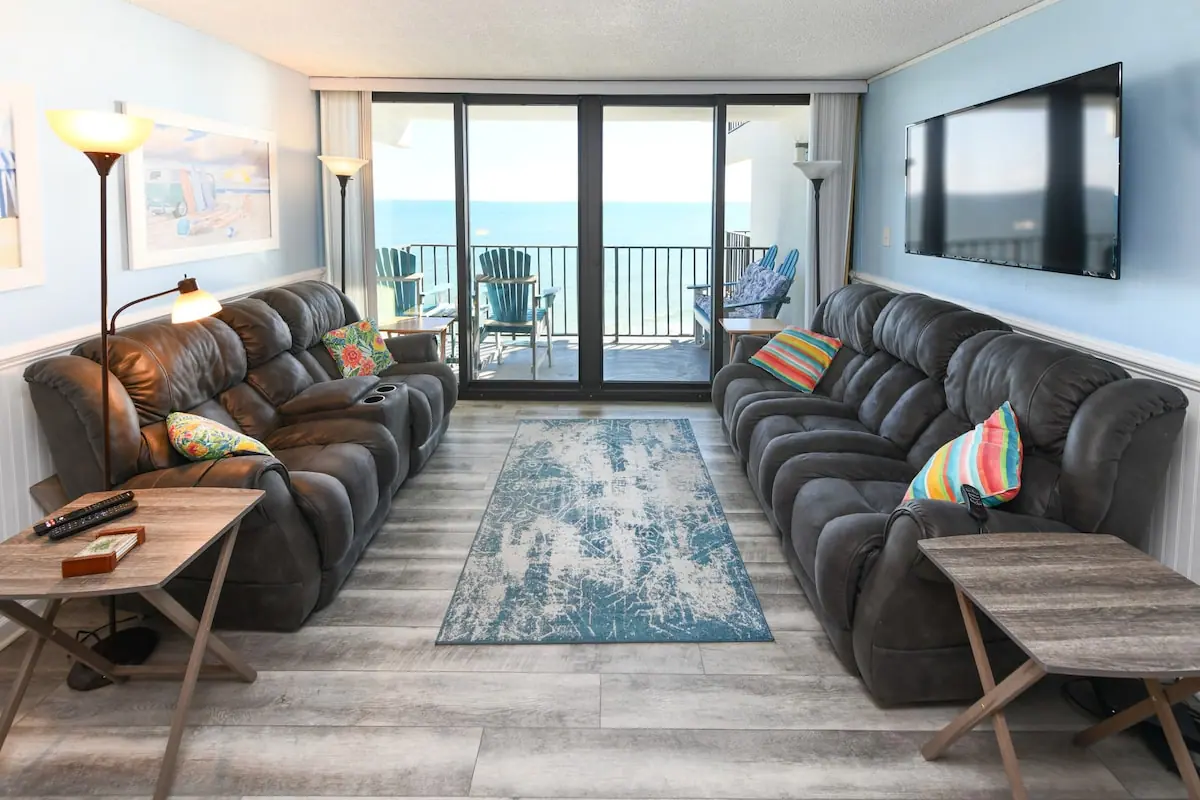 Living room with dark sofas and glass doors to an ocean balcony