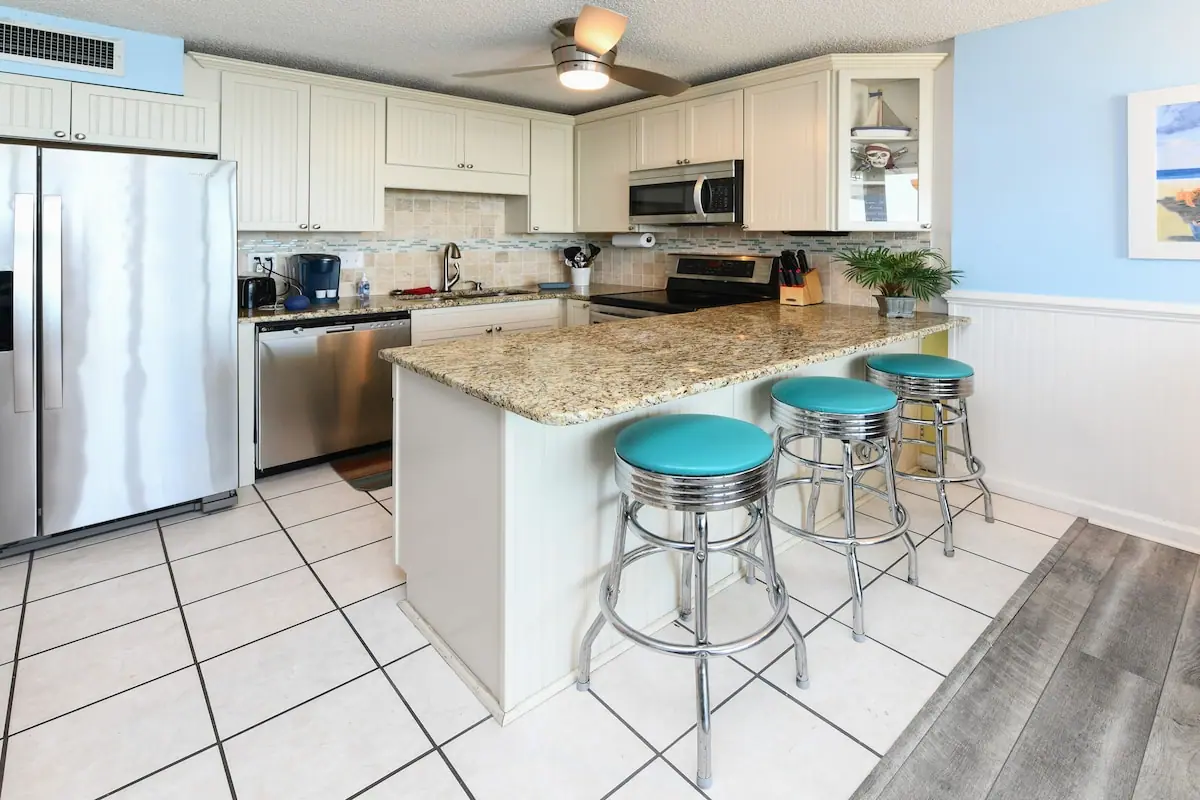White kitchen with granite breakfast bar and turquoise stools