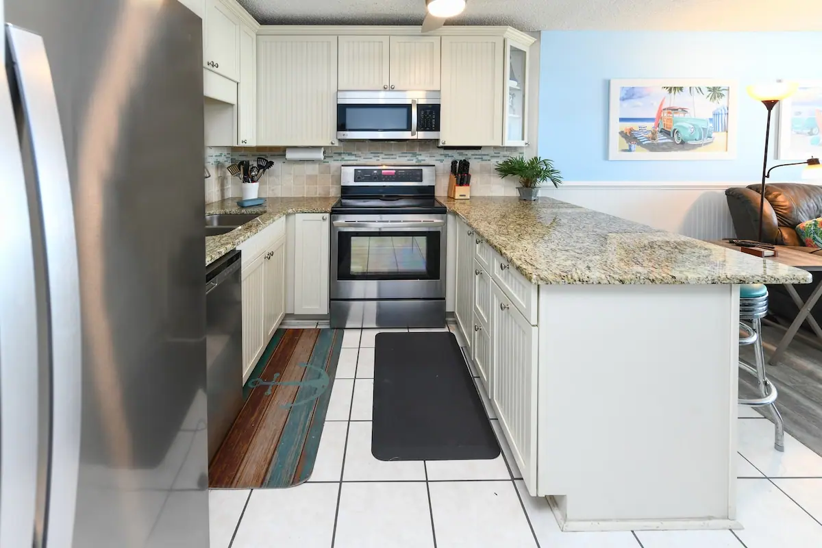White kitchen with stainless stove and granite breakfast bar