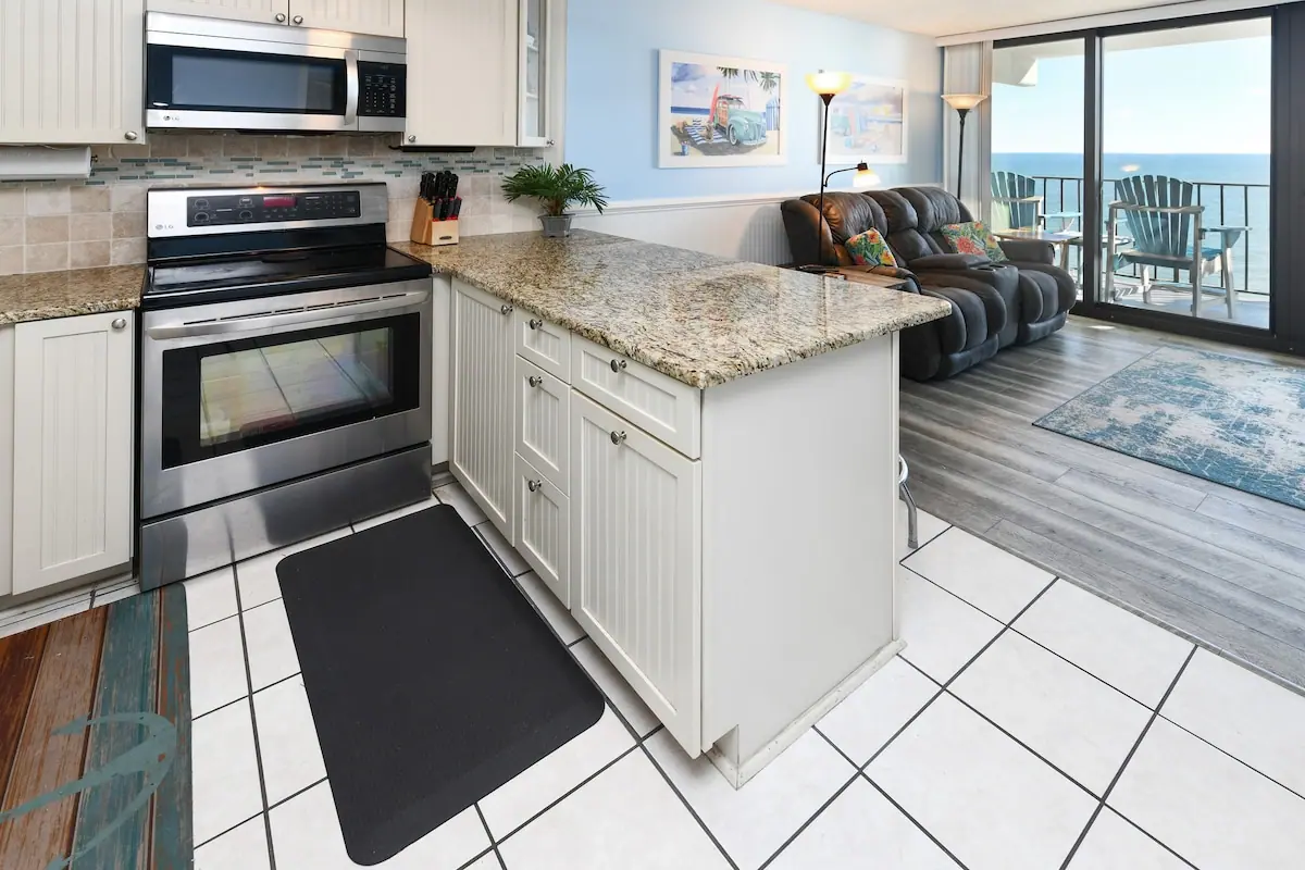 Kitchen breakfast bar opening to a living room and ocean balcony