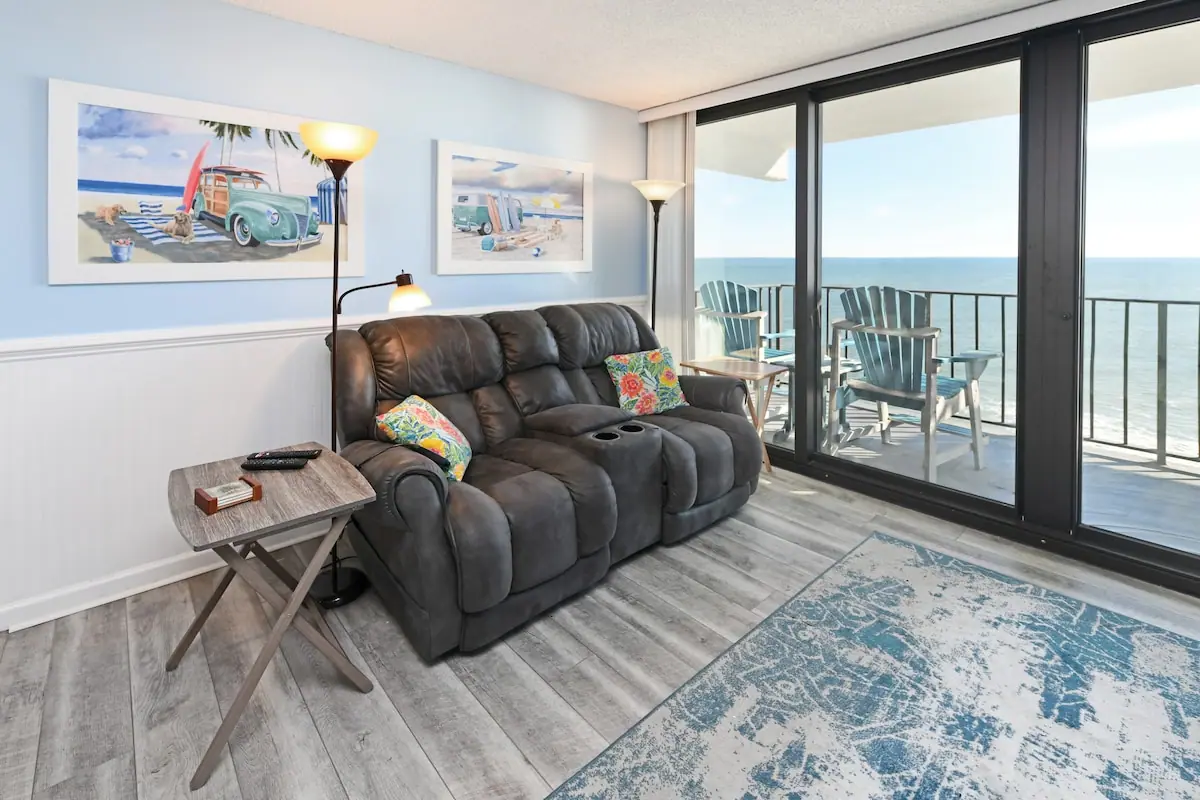 Dark sofa beside glass balcony doors overlooking the ocean