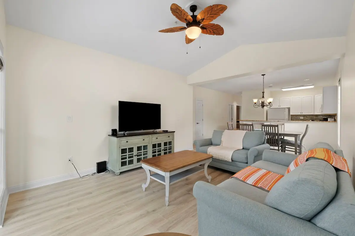 Living room with gray sofa and television, open kitchen behind