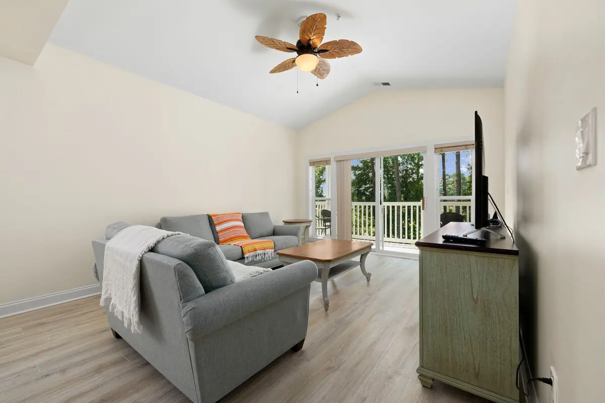 Gray sofa and chair facing television with trees through patio doors