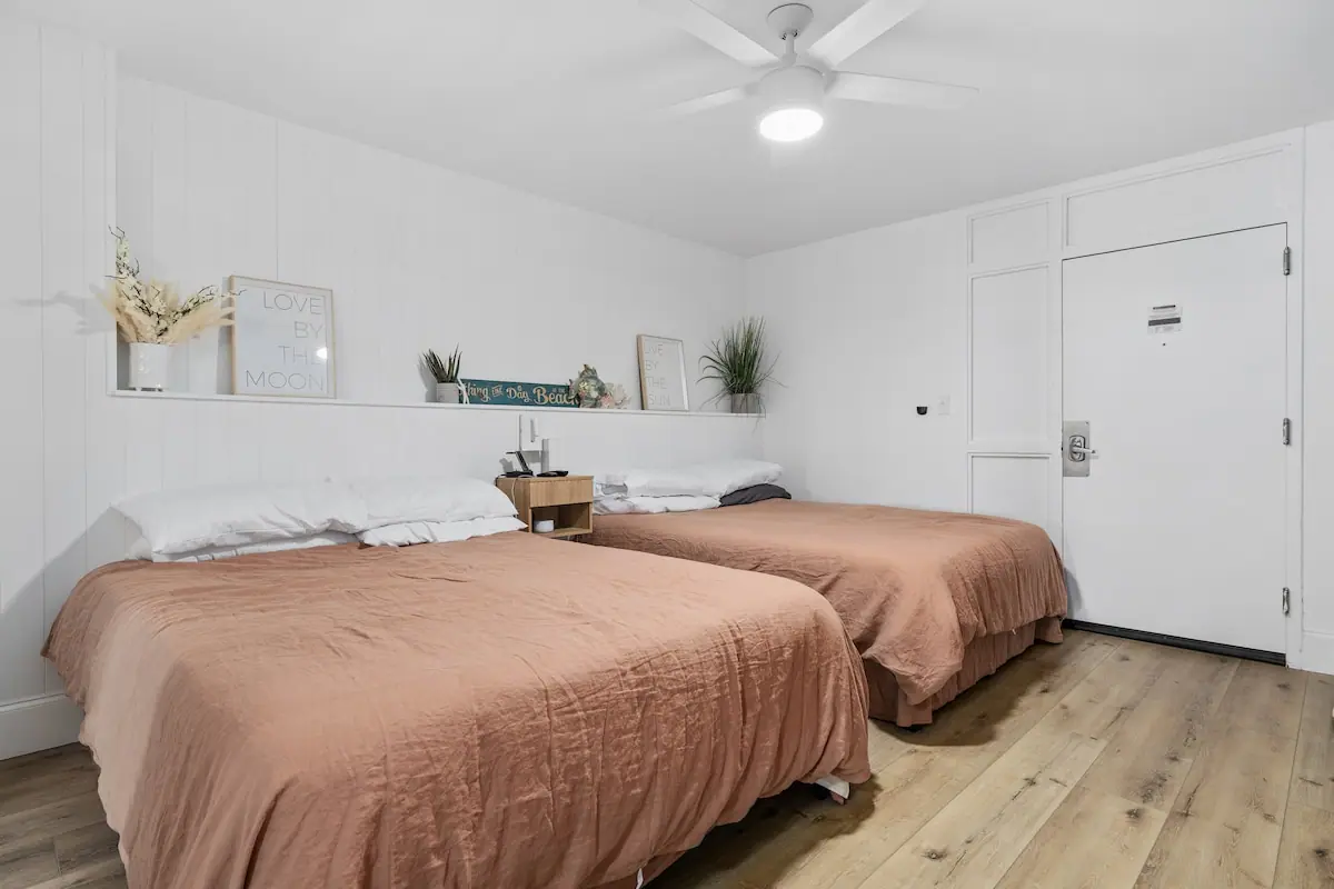 White bedroom with two beds covered in peach-colored blankets