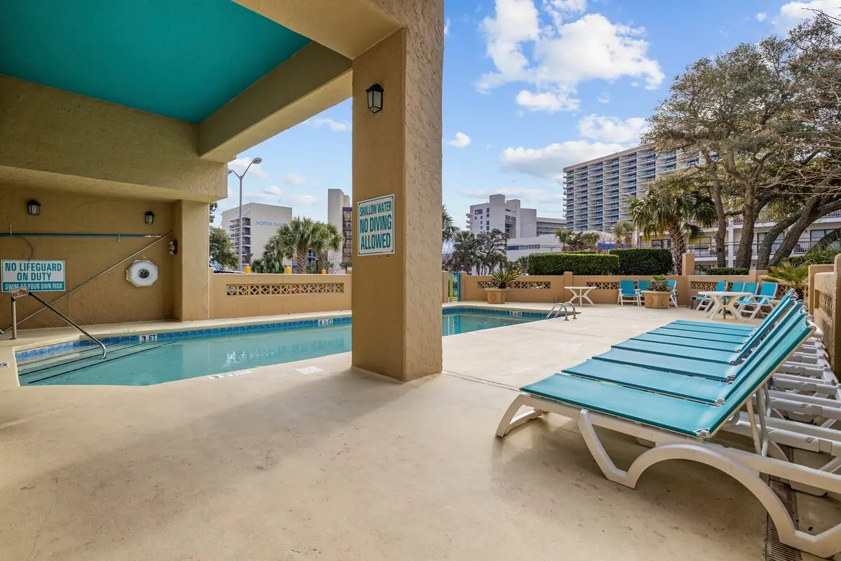 Covered outdoor pool beside turquoise lounge chairs