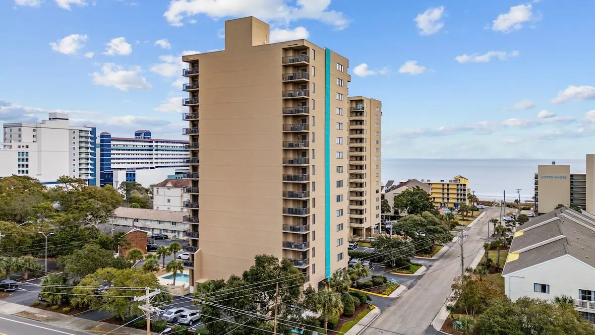 View past a tan high-rise toward a coastal street and the ocean