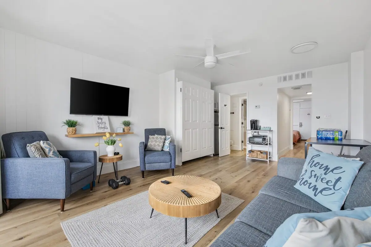 Bright living area with blue chairs, gray sofa, and television