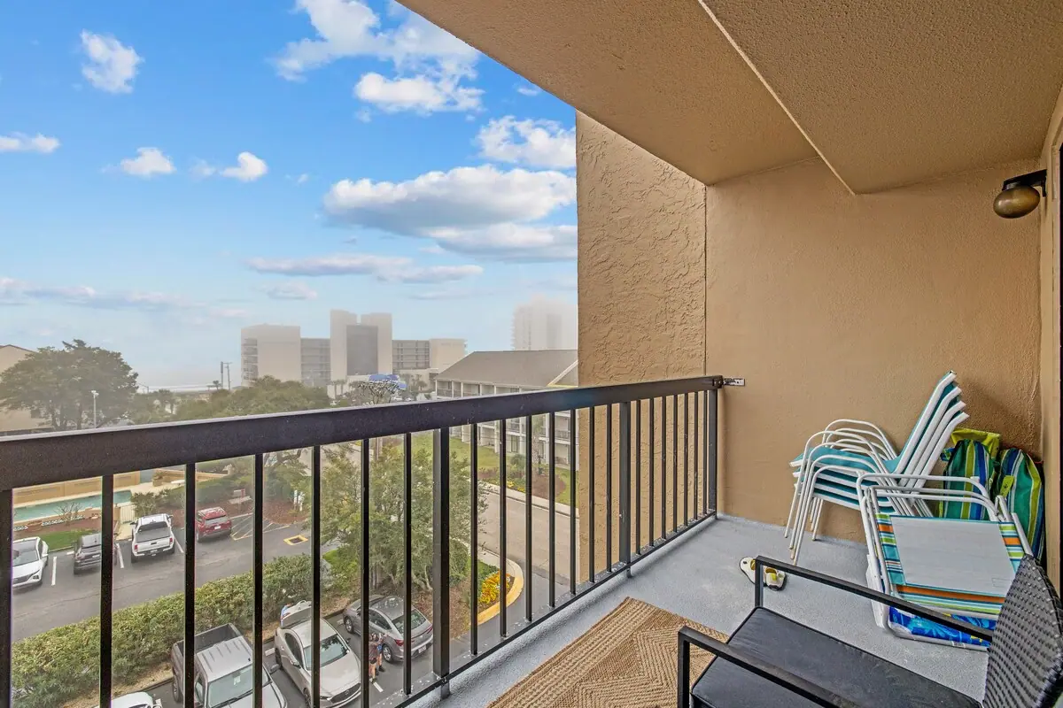 Balcony with striped chairs overlooking nearby buildings toward the ocean