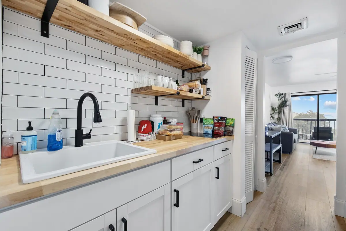 Compact kitchen with white tile backsplash and open wooden shelves
