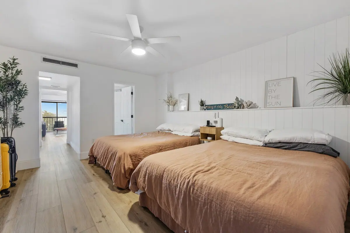 Two beds with peach-colored blankets beside a white wall shelf