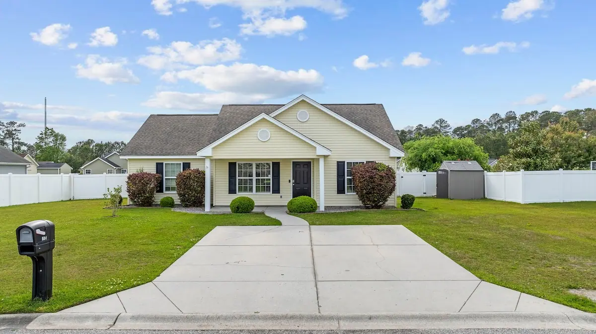 Single-story yellow cottage with a front lawn and driveway