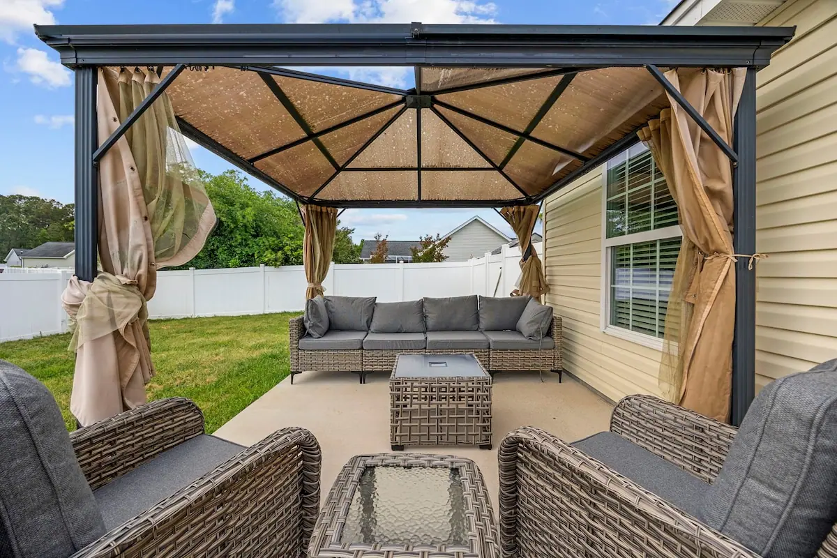 Backyard patio seating beneath a curtained canopy