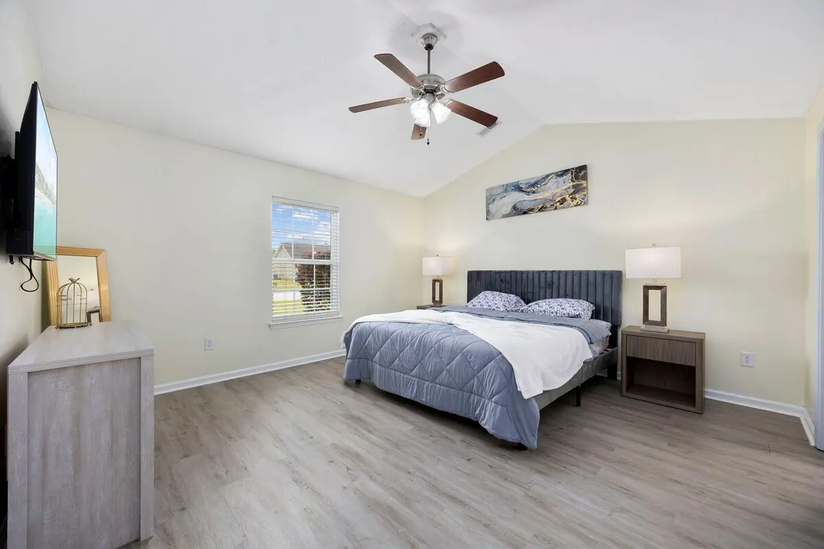 Bedroom with gray bed, wall-mounted television, and wood floor