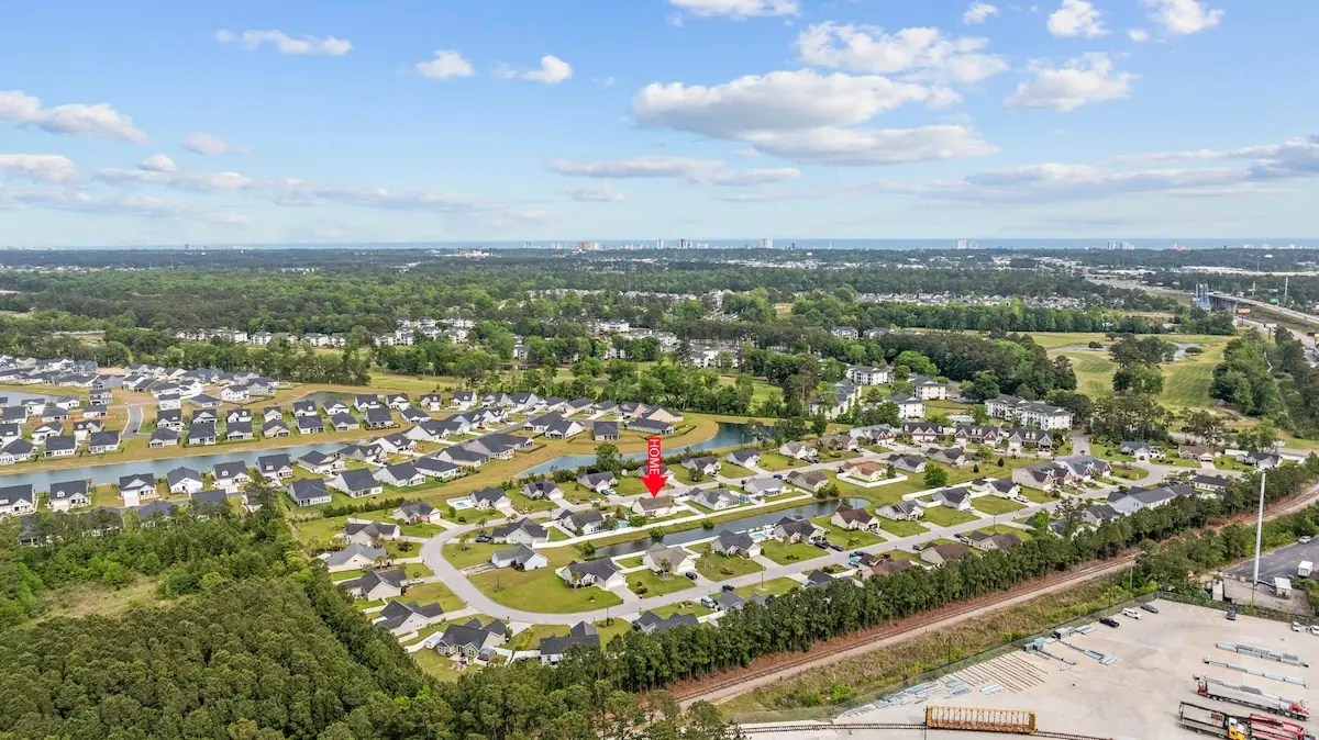 High aerial view of a neighborhood bordered by trees and open green space